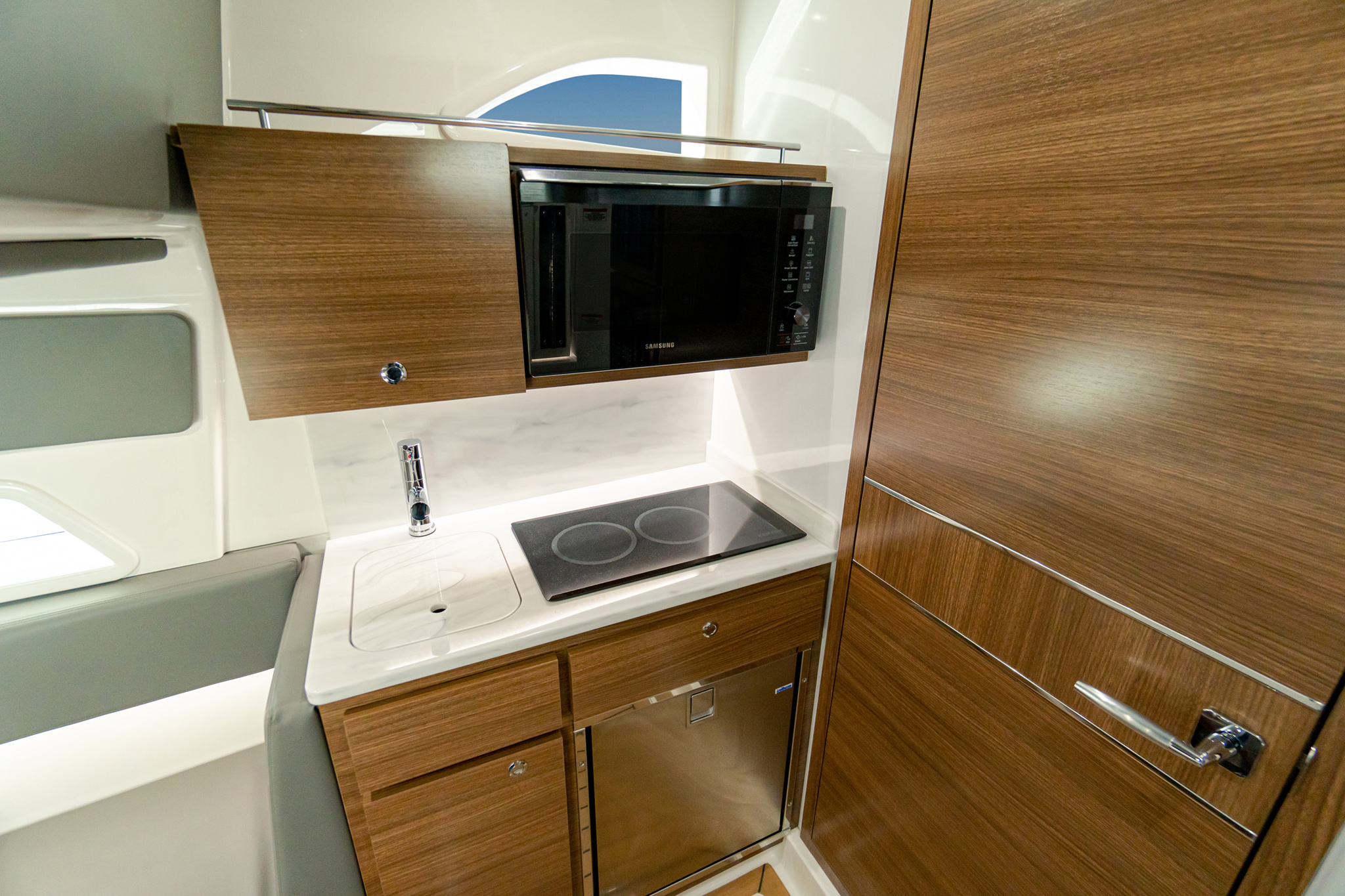 Galley features Corian counter, two-burner stove, stainless steel sink, microwave, fridge/freezer and storage.